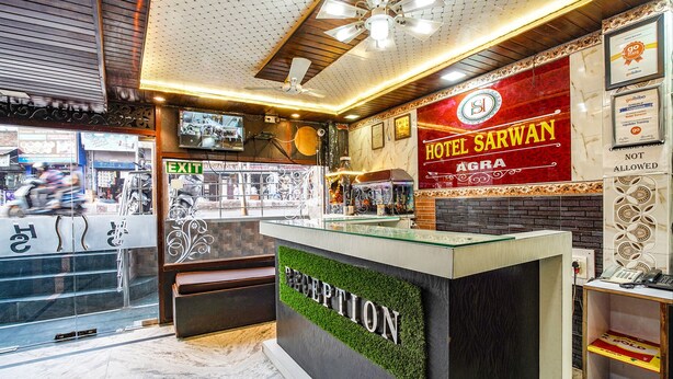 A hotel reception area with a reception desk, a sign for Hotel Sarwan, and an exit sign. - Fabhotel Sarwan (Agra)