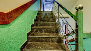 A staircase with a green wall on one side and a metal railing on the other. - Fabhotel Hill View (Madikeri)