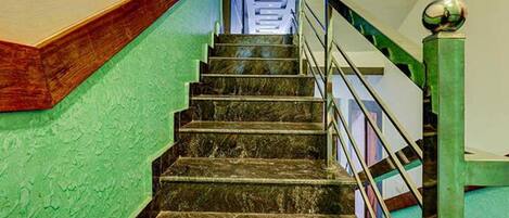Una escalera con una pared verde a un lado y una barandilla de metal al otro.