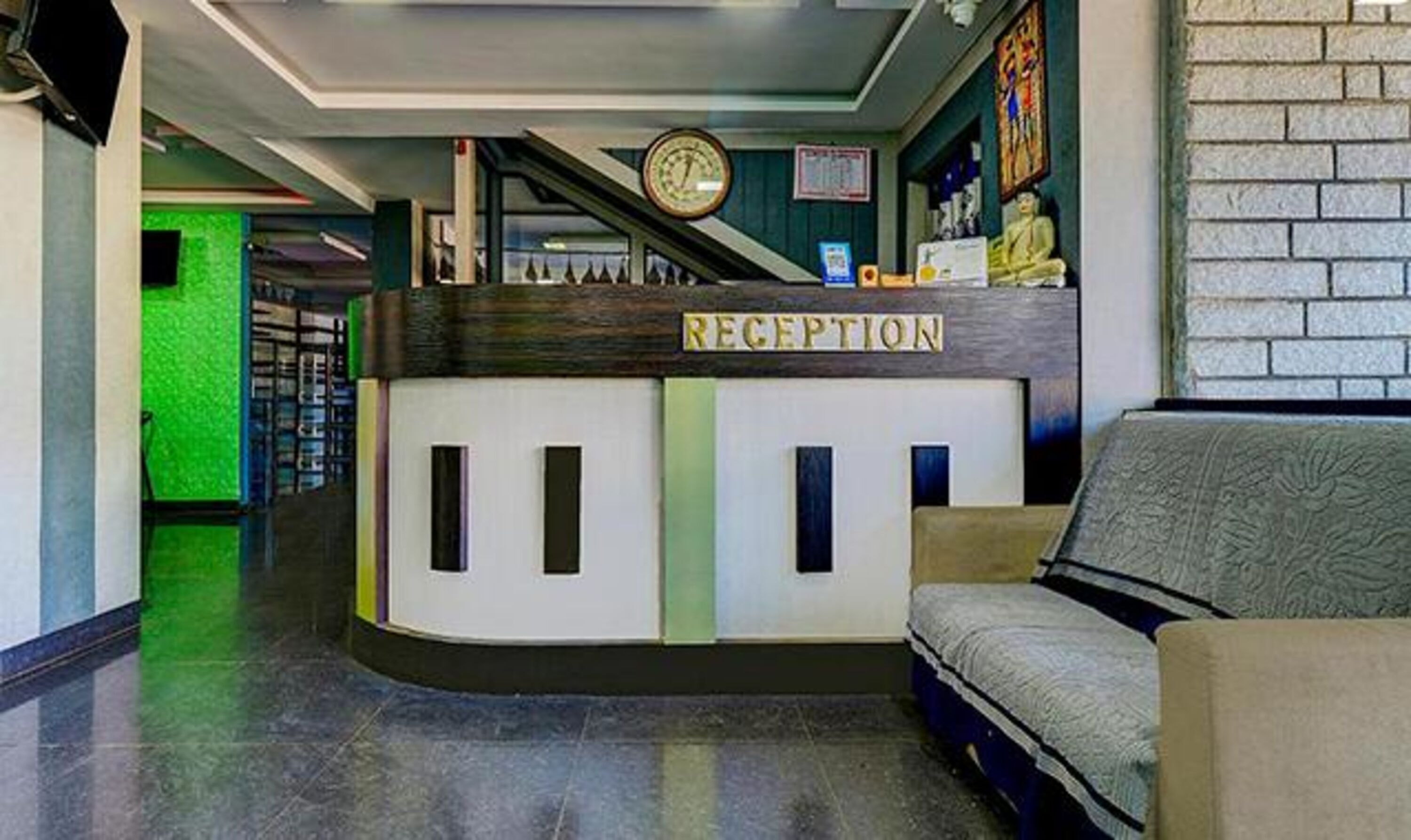 A reception desk with a clock above it, a sofa, and a brick wall in the background.