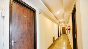 Corredor de hotel com portas de madeira, extintor de incêndio e placa indicando o quarto número 102.