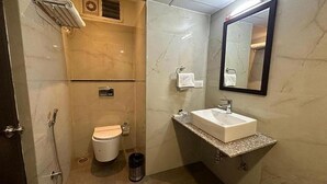 A bathroom with a toilet, sink, mirror, towel rack, and shower. - Fabhotel Prime Landridge (Hyderabad)