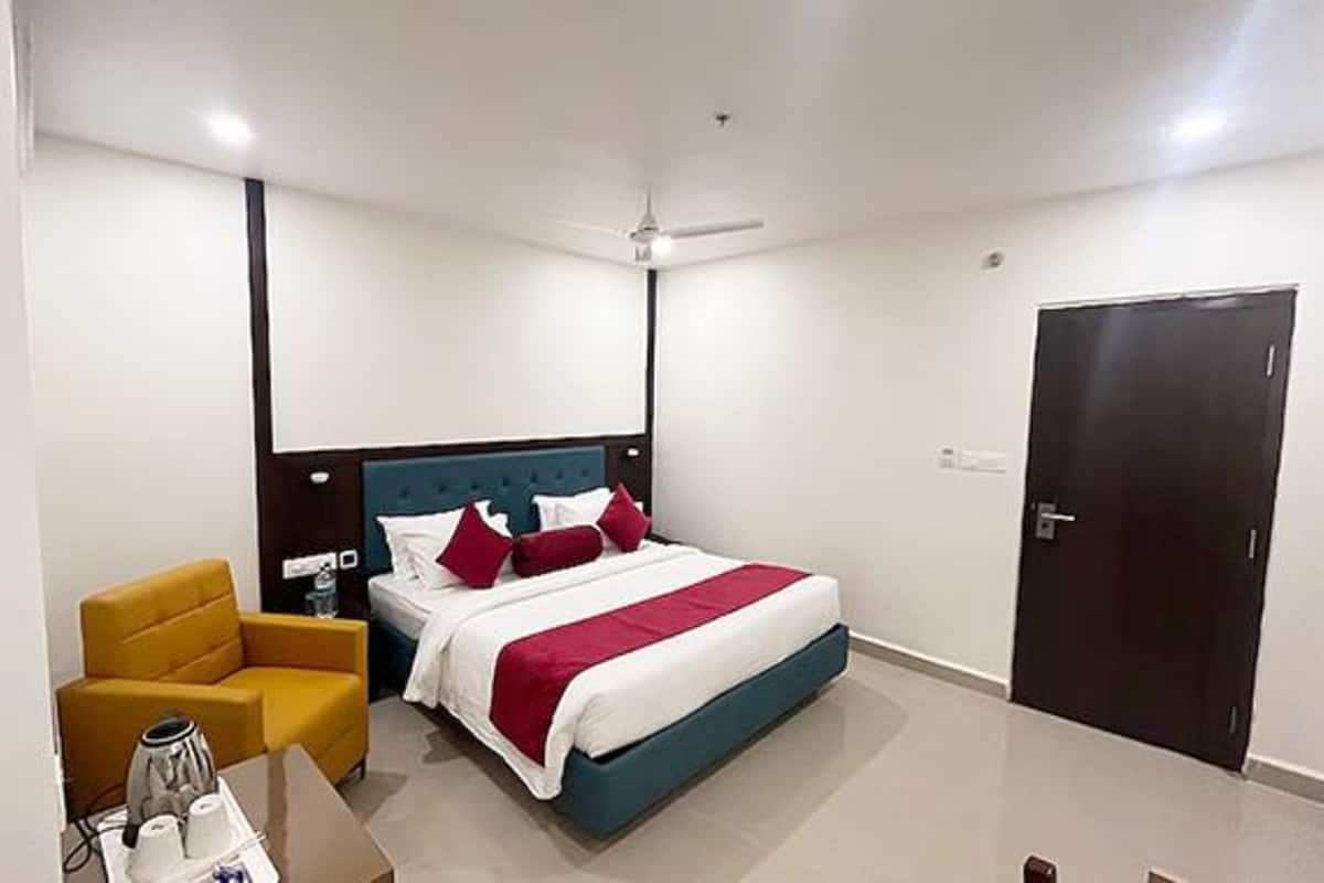 Habitació d'hotel amb llit, cadira, escriptori i armari.