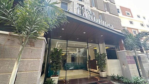 A hotel entrance with a modern design, featuring a glass facade and a stone facade. - Fabhotel Prime Landridge (Hyderabad)