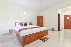Un dormitorio con una cama de madera, un armario, una mesita de noche y un cubo de basura.
