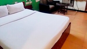 A hotel room with a large bed, a small table, and a chair. - Fabhotel Satlaj (Raipur)