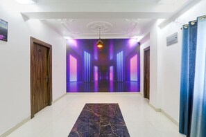 A hallway with a marble floor, a wooden door on the left, and a blue curtain on the right. - Fabexpress Magadh Glory (Danapur)