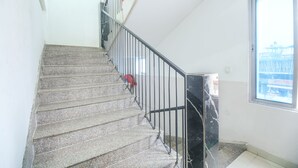 A staircase with a metal railing, a window with a view of a bridge, and a red object on the wall. - Fabexpress Sai Villa (Guwahati)