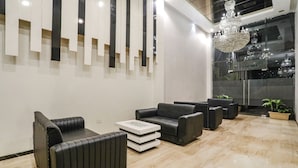 A modern interior with black leather sofas, a marble floor, and a chandelier. - Fabhotel Prime Mahendra (Raipur)