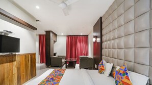 A hotel room with a bed, a TV, a desk, and two chairs. - Fabhotel Prime Mahendra (Raipur)