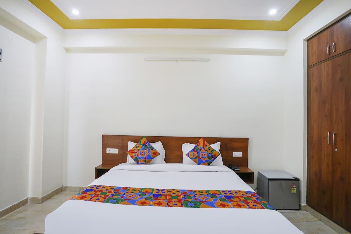 Een hotelkamer met een bed, een nachtkastje, een kledingkast en een kleine koelkast.