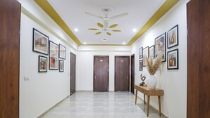 A hallway with a tiled floor, wooden doors, and framed artwork on the walls. - FabHotel Star Corporate Suite I (Gurugram)