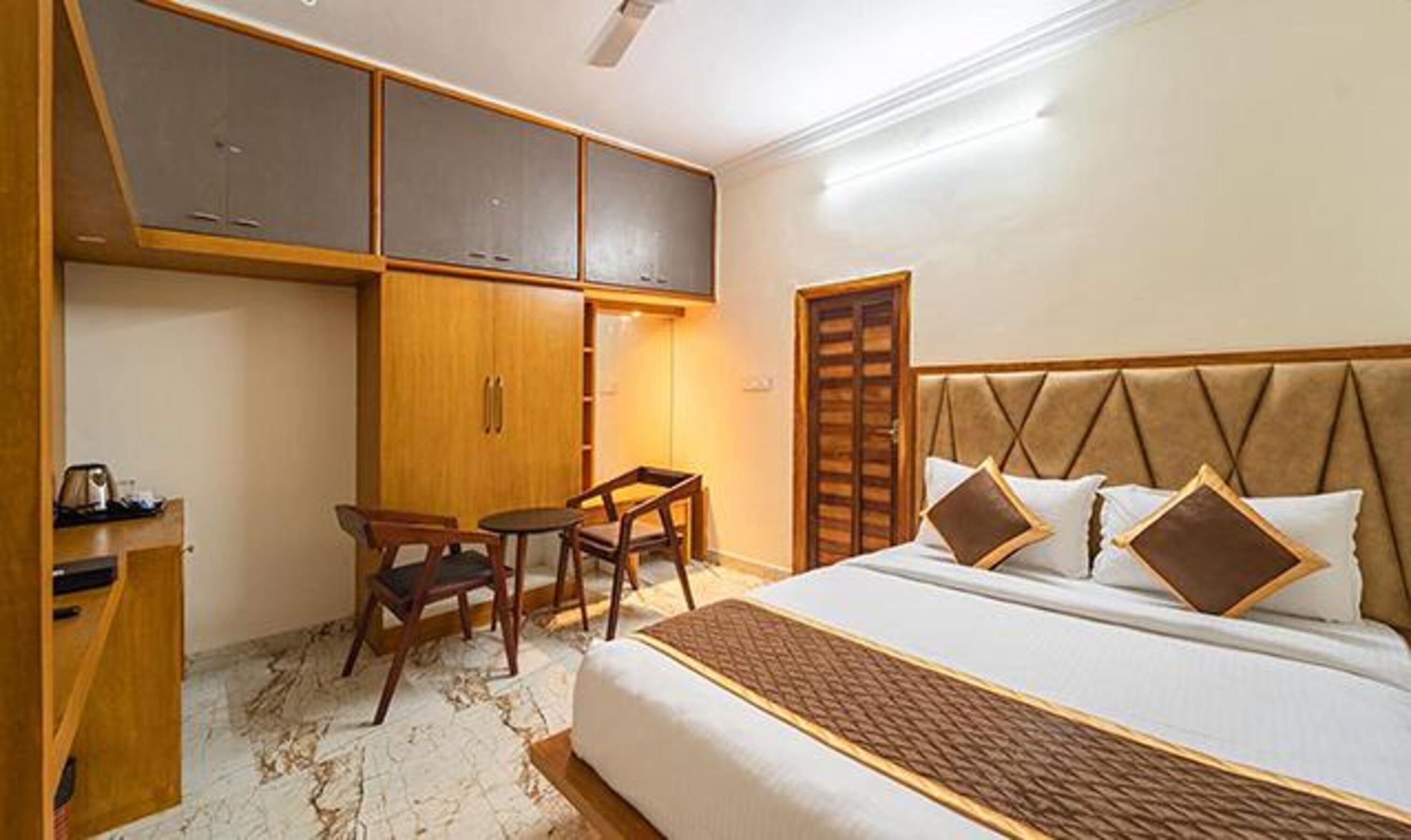 Une chambre d’hôtel avec un lit, un bureau, une chaise et une armoire.