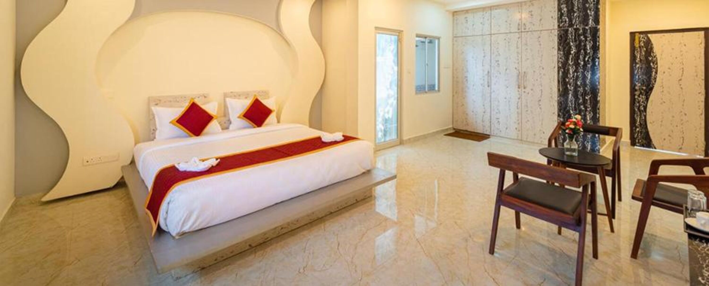Une chambre d’hôtel moderne avec un grand lit, une petite table et un banc.