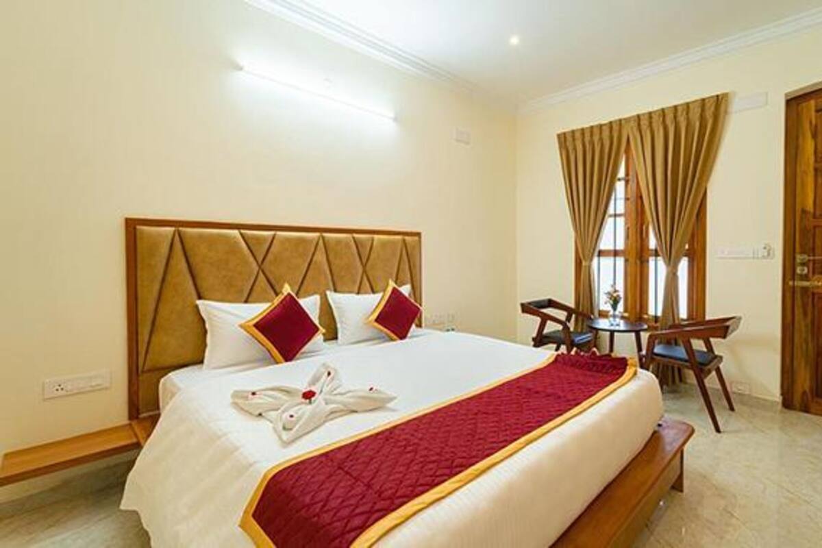 Une chambre d’hôtel avec un grand lit, une tête de lit en bois, une table à manger avec des chaises et une porte en bois.