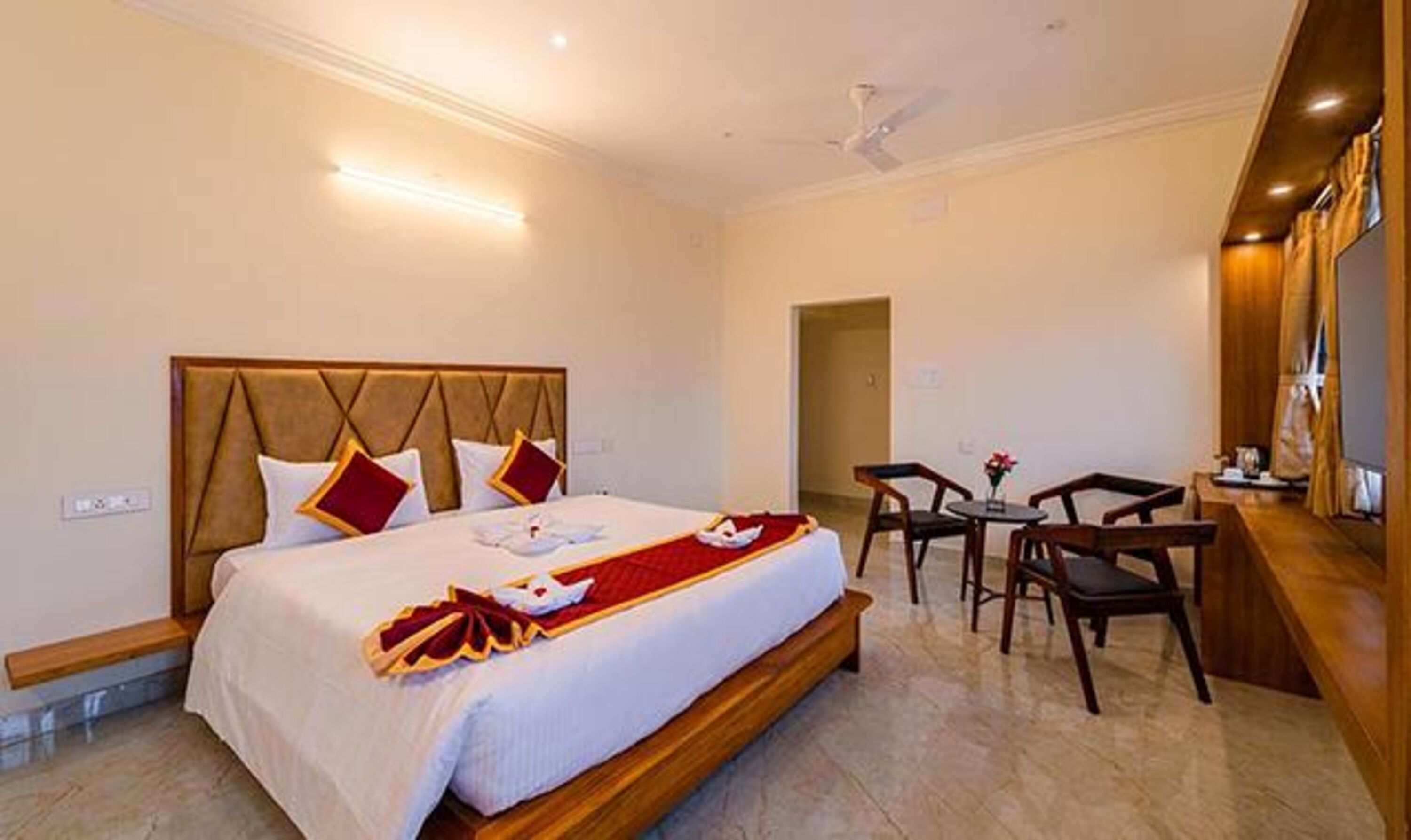 Ein Hotelzimmer mit einem großen Bett, einem kleinen Tisch mit Stühlen und einem Deckenventilator.