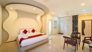 A modern hotel room with a large bed, a dining area, and a bathroom with a large mirror. - Fabhotel Prime Ar Phalazzo Resort (Vanur)