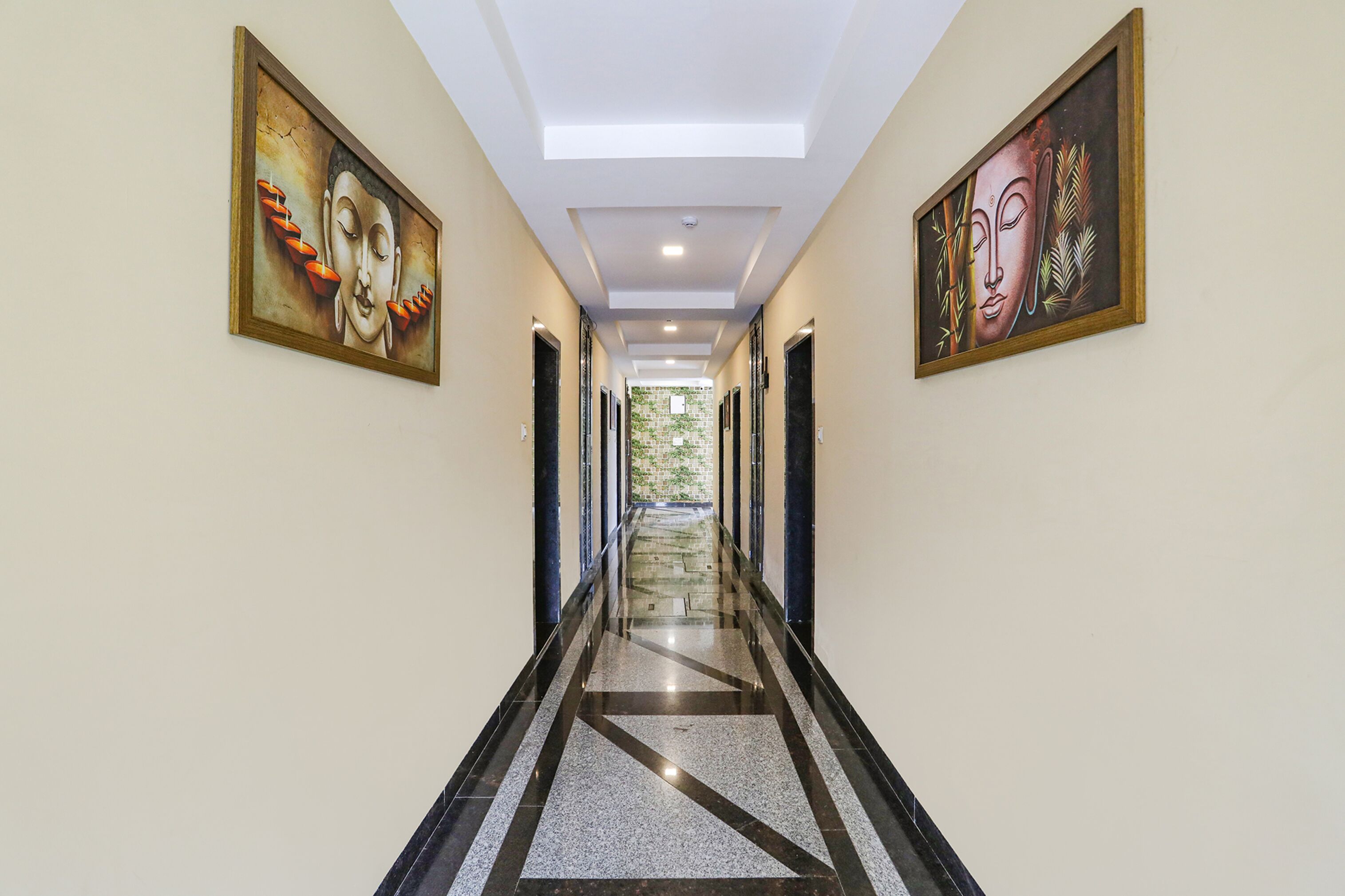 A hallway with two framed artworks on the walls, a skylight, and a patterned floor.