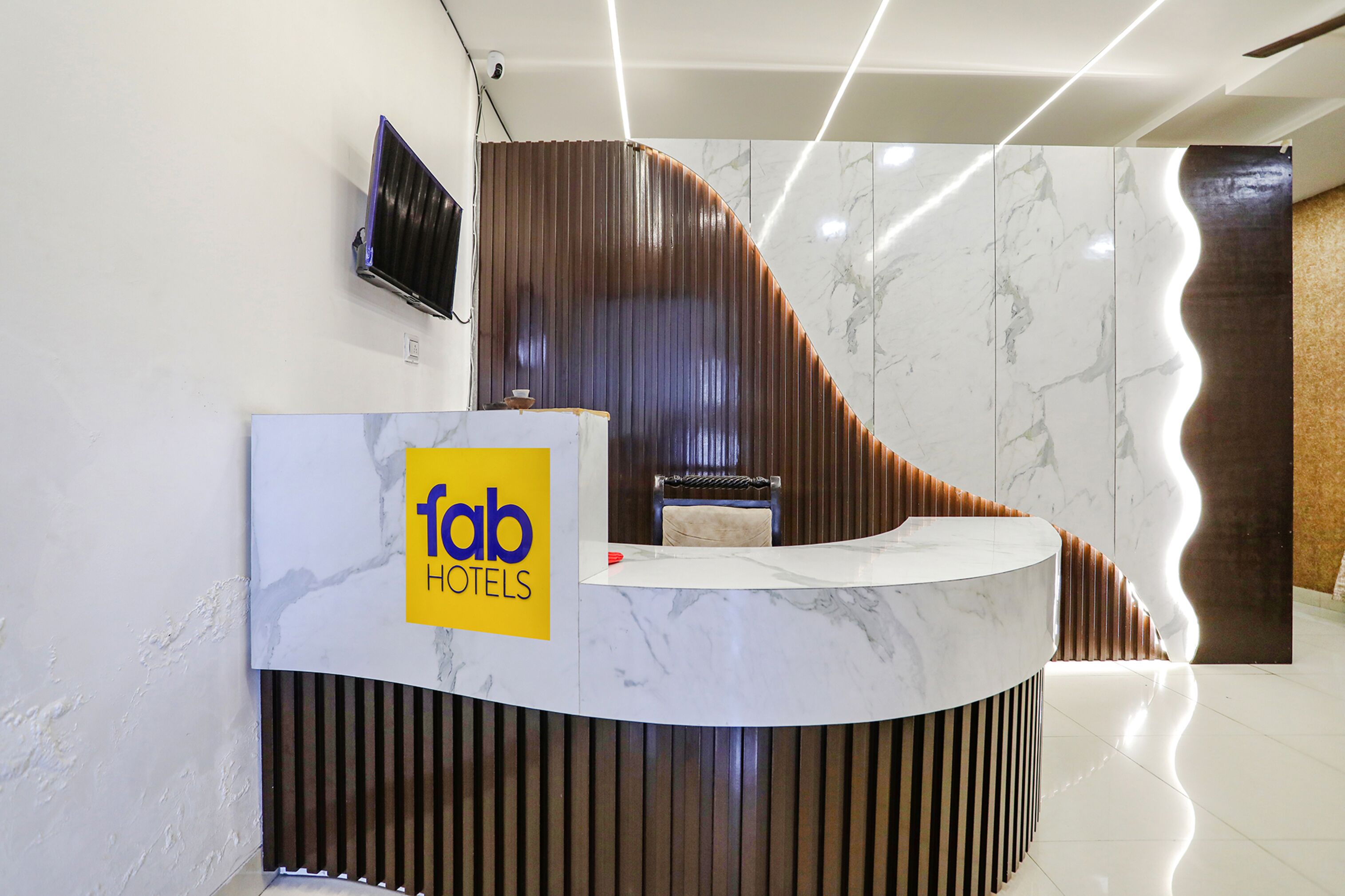 A modern reception desk with a marble top, a television mounted on the wall, and a logo for 'fab hotels'.