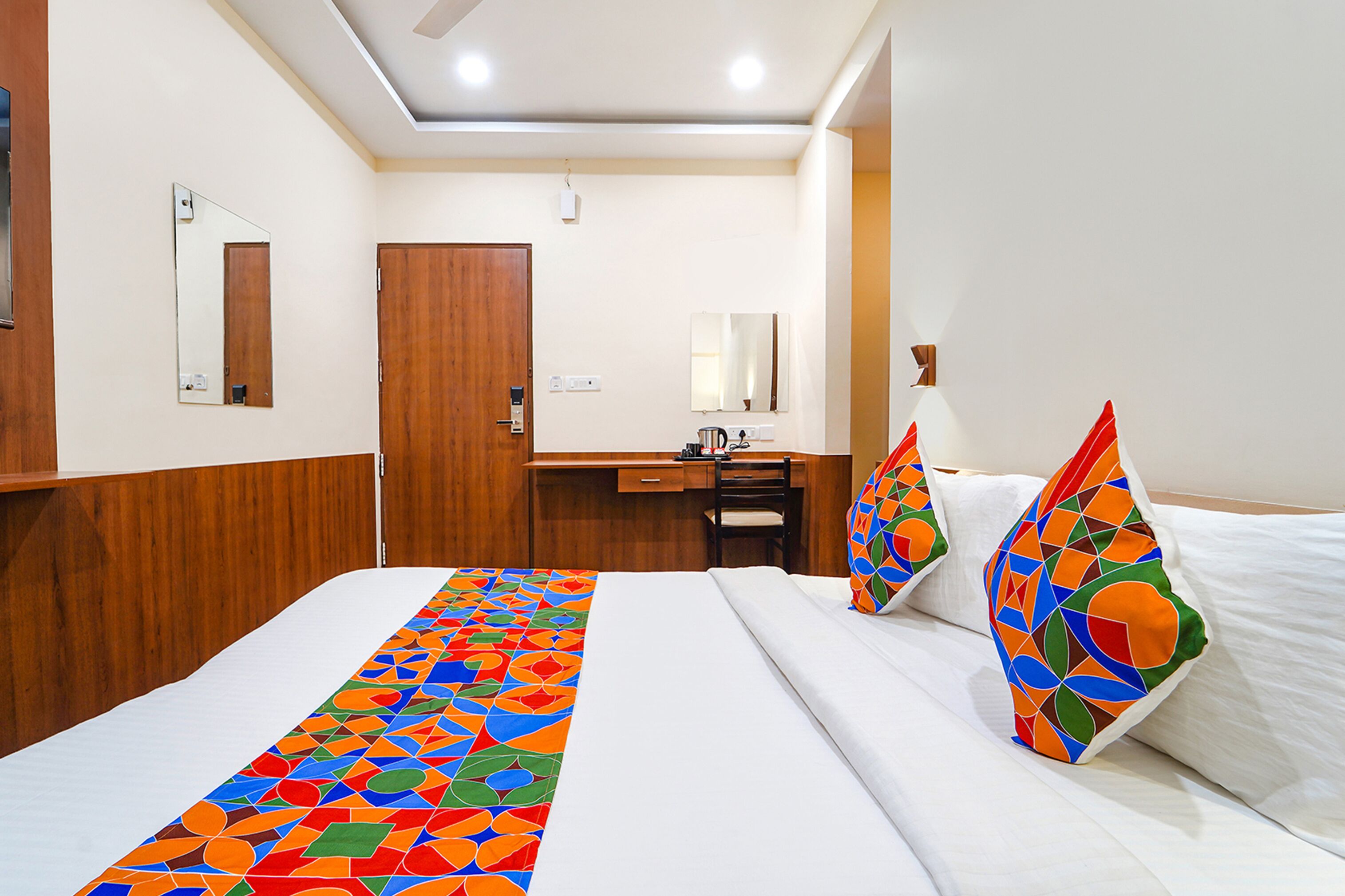 A hotel room with a bed, a desk, and a mirror.