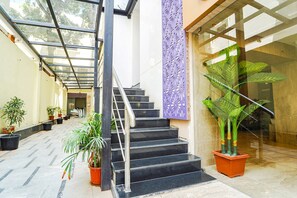 A staircase with metal railings, potted plants, and a glass door leading to a room. - Fabhotel Stayz Inn Us Consulate (Chennai)