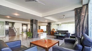 A spacious lobby with a wooden coffee table, leather sofas, and a staircase leading to an upper floor. - Fabhotel Interglobe Oasis (Gurugram)