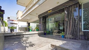 A modern building with a marble entrance and potted plants. - Fabhotel Interglobe Oasis (Gurugram)