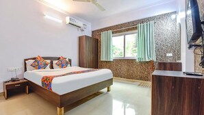 A hotel room with a bed, a desk, a wardrobe, and a window with curtains. - Fabexpress Springs (Alto de Porvorim)