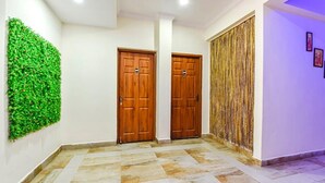 A hallway with two wooden doors, a green wall, and a patterned curtain. - Fabexpress Springs (Alto de Porvorim)
