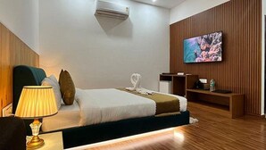 A hotel room with a bed, a TV, a lamp, and a wooden wall panel. - Fabhotel Prime The Aravali Resort (Yamkeshwar)