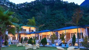 A resort with multiple buildings, outdoor seating, and a mountainous backdrop. - Fabhotel Prime The Aravali Resort (Yamkeshwar)