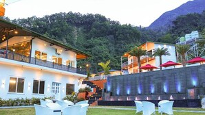 A two-story building with a balcony, outdoor seating area, and a water feature. - Fabhotel Prime The Aravali Resort (Yamkeshwar)