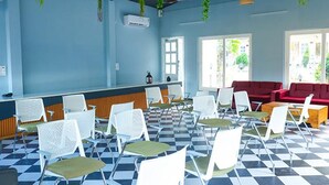 A room with a checkered floor, white chairs, a red sofa, and a counter with a plant hanging above. - Fabhotel Prime The Aravali Resort (Yamkeshwar)