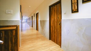 Un pasillo de hotel con puertas de madera, un muro de mármol y suelo de madera.