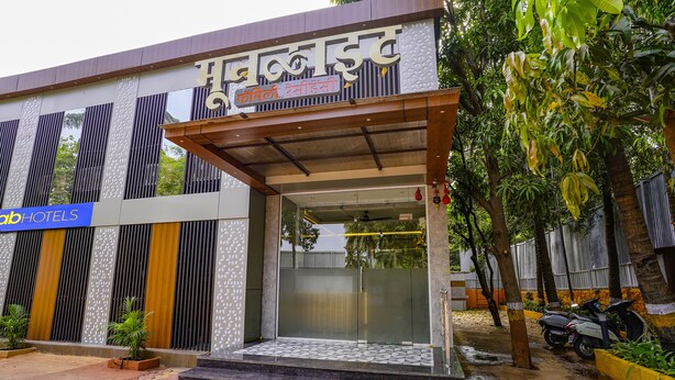 Entrada de hotel con diseño moderno, que presenta una puerta de cristal y un área de acceso cubierta.