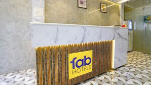 Zona de recepción de hotel con mostrador de mármol, un cartel de 'Tab Hotels' y un suelo estampado.
