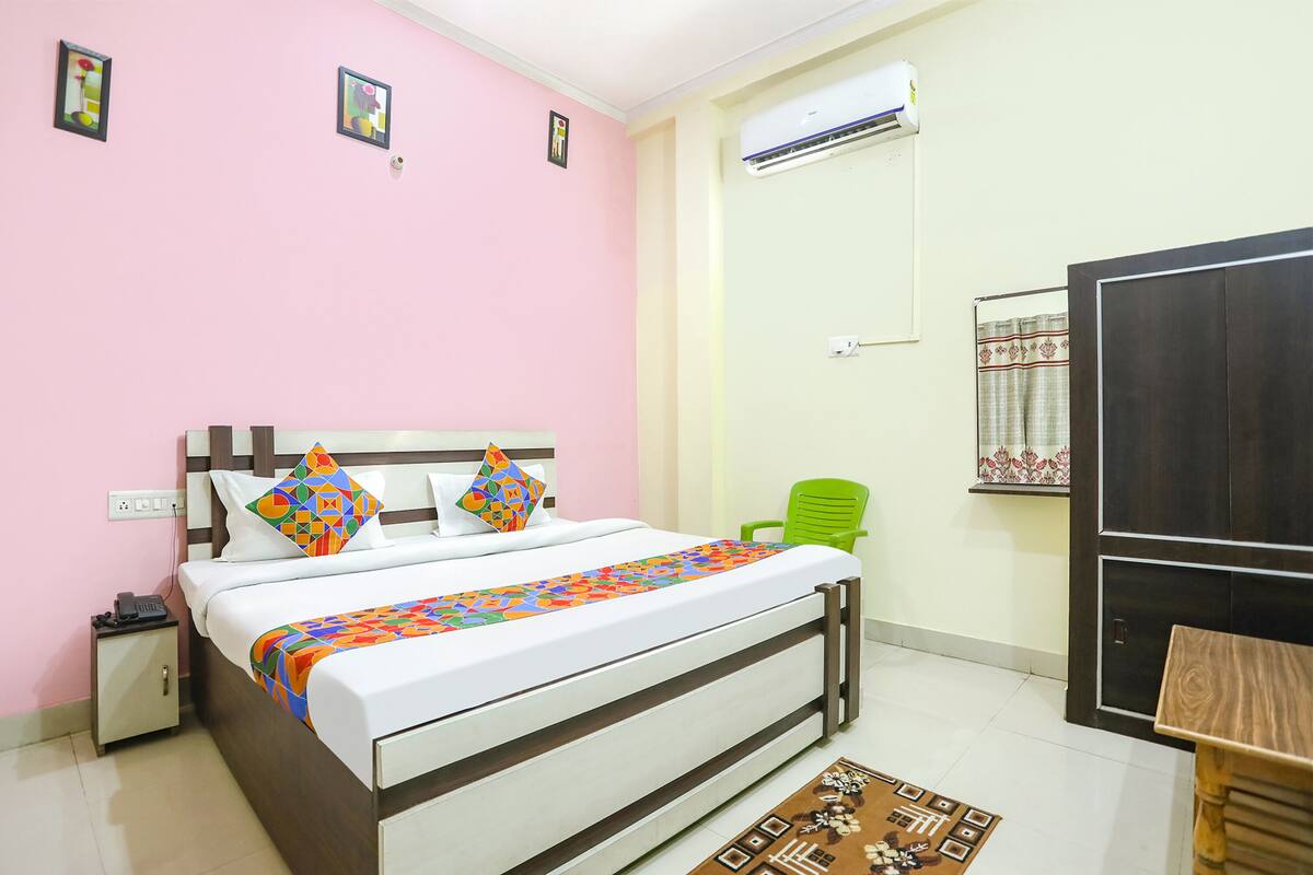 Une chambre à coucher comprenant un lit, une table de chevet, une chaise, une armoire et une petite table sur laquelle sont posés divers objets.