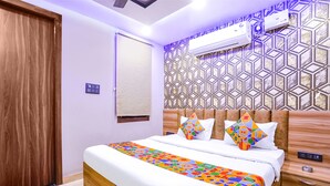 Una cama impecablemente tendida con una colcha de diseño geométrico y colores vivos, un cabecero de madera y una mesita de noche a juego con un cajón.