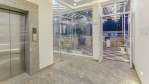 An elevator, a glass door entrance, and a checkered floor. - FabHotel Ramana (Udaipur)