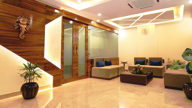 A modern lobby with a wooden accent wall, a reception desk, and seating area with sofas and a coffee table. - FabHotel Ramana (Udaipur)