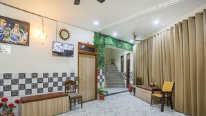 A reception area with a check-out time sign, a television, a staircase, and a reception desk. - Fabexpress Dau Ji Residency (Mathura)