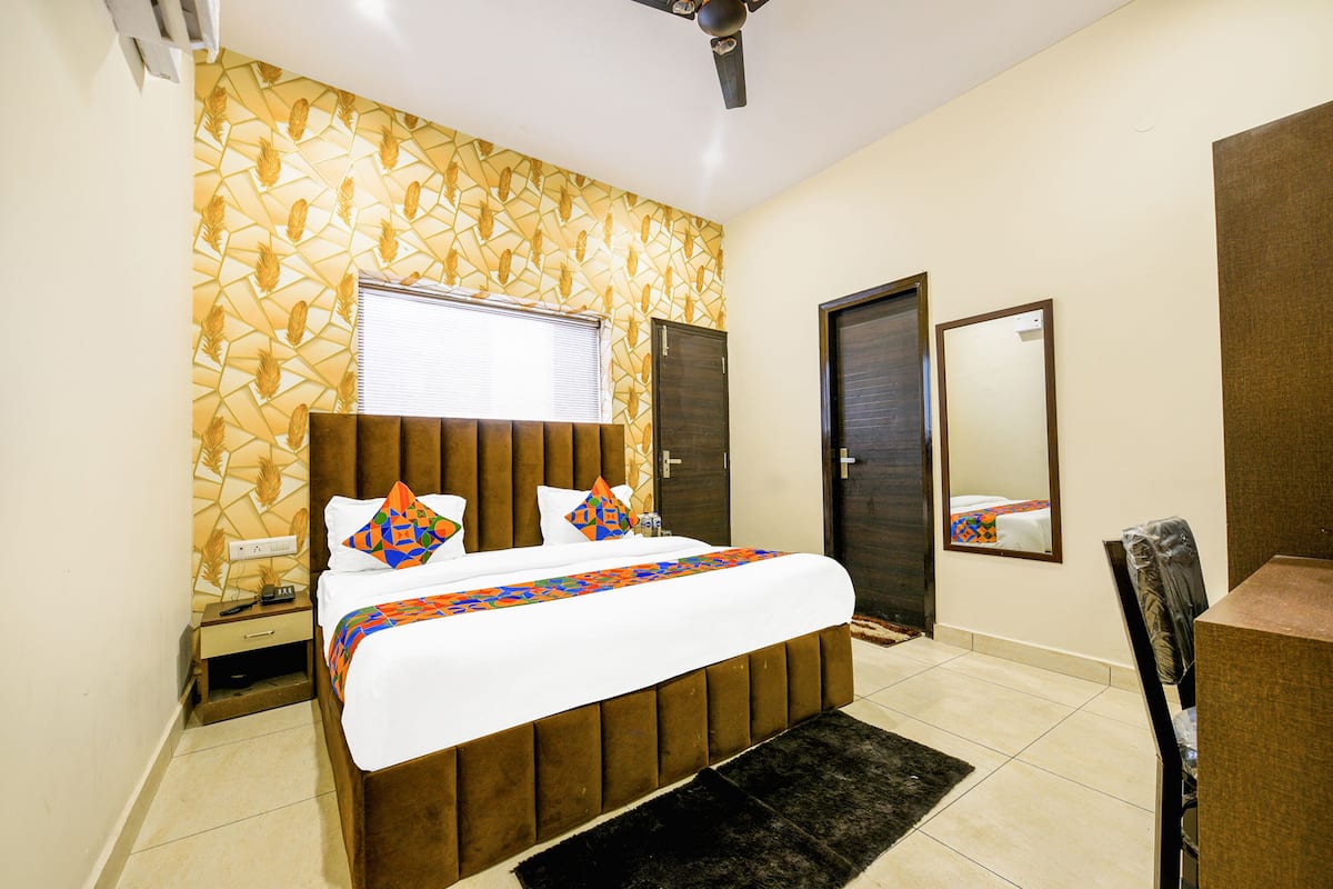 A bedroom with a bed, bedside table, and a mirror on the wall.