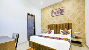Quarto de hotel com cama, mesa de cabeceira, cadeira e porta.