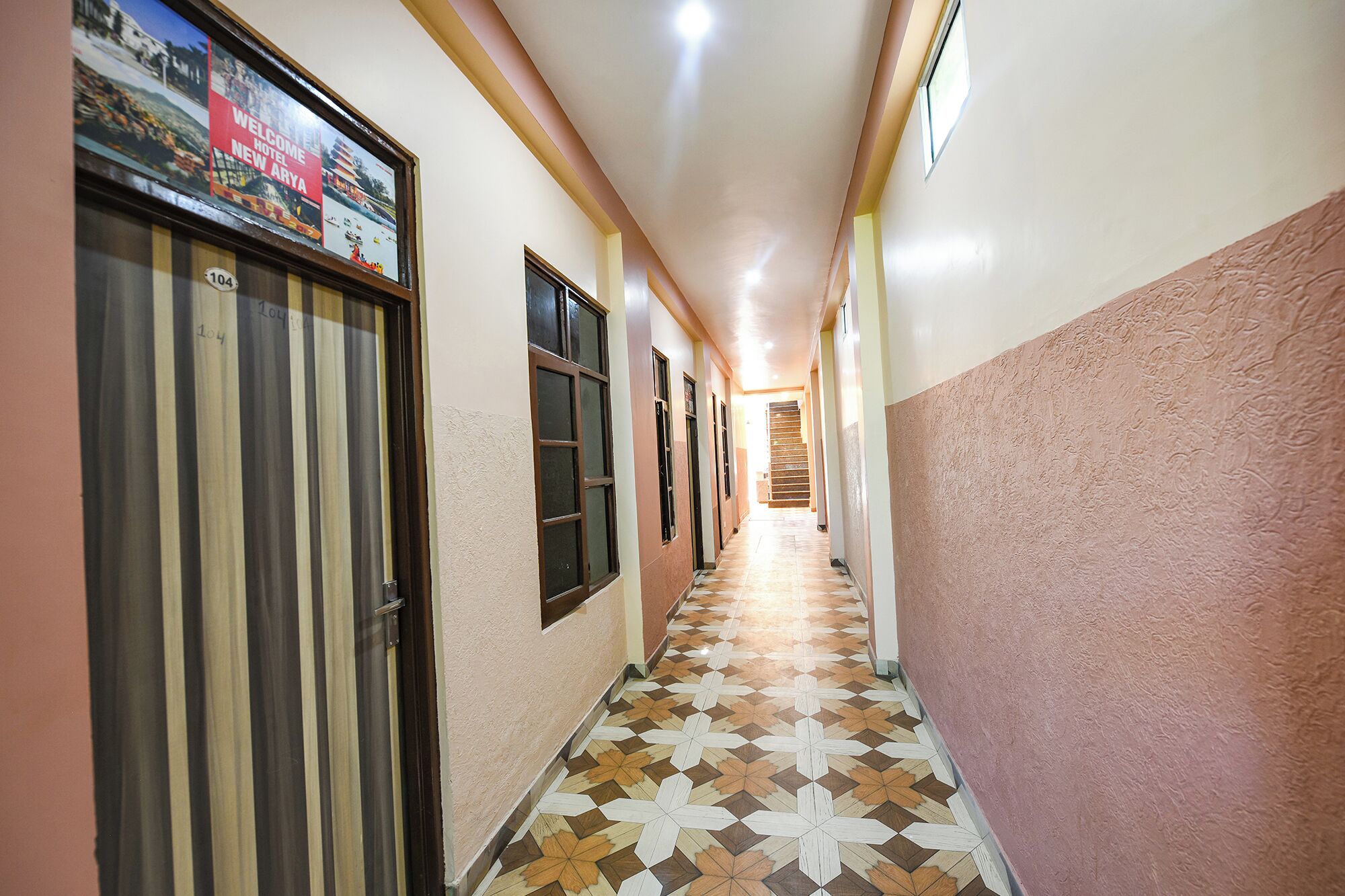 A hotel hallway with patterned flooring, doors, and a signboard.