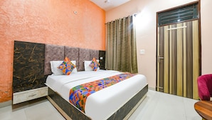 A hotel room with a bed, a wardrobe, a bathroom, and a small table. - Fabexpress Galaxy (Kharar)