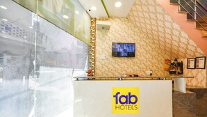 A reception desk with a 'fab hotels' sign, a mounted television, and a patterned wall. - Fabexpress Galaxy (Kharar)