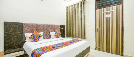 A bedroom with a bed, curtains, a door, and a marble headboard.