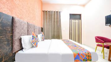 A hotel room with a large bed, a TV mounted on the wall, and a small table with a chair.
