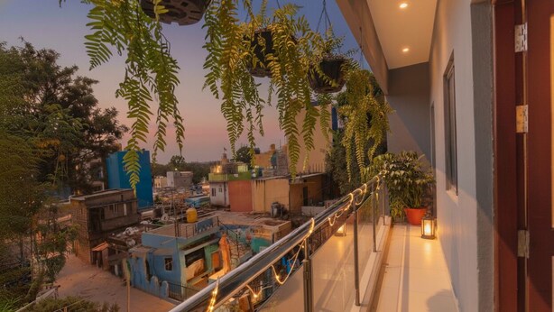 Un balcón con plantas colgantes y vista a un paisaje urbano al atardecer.