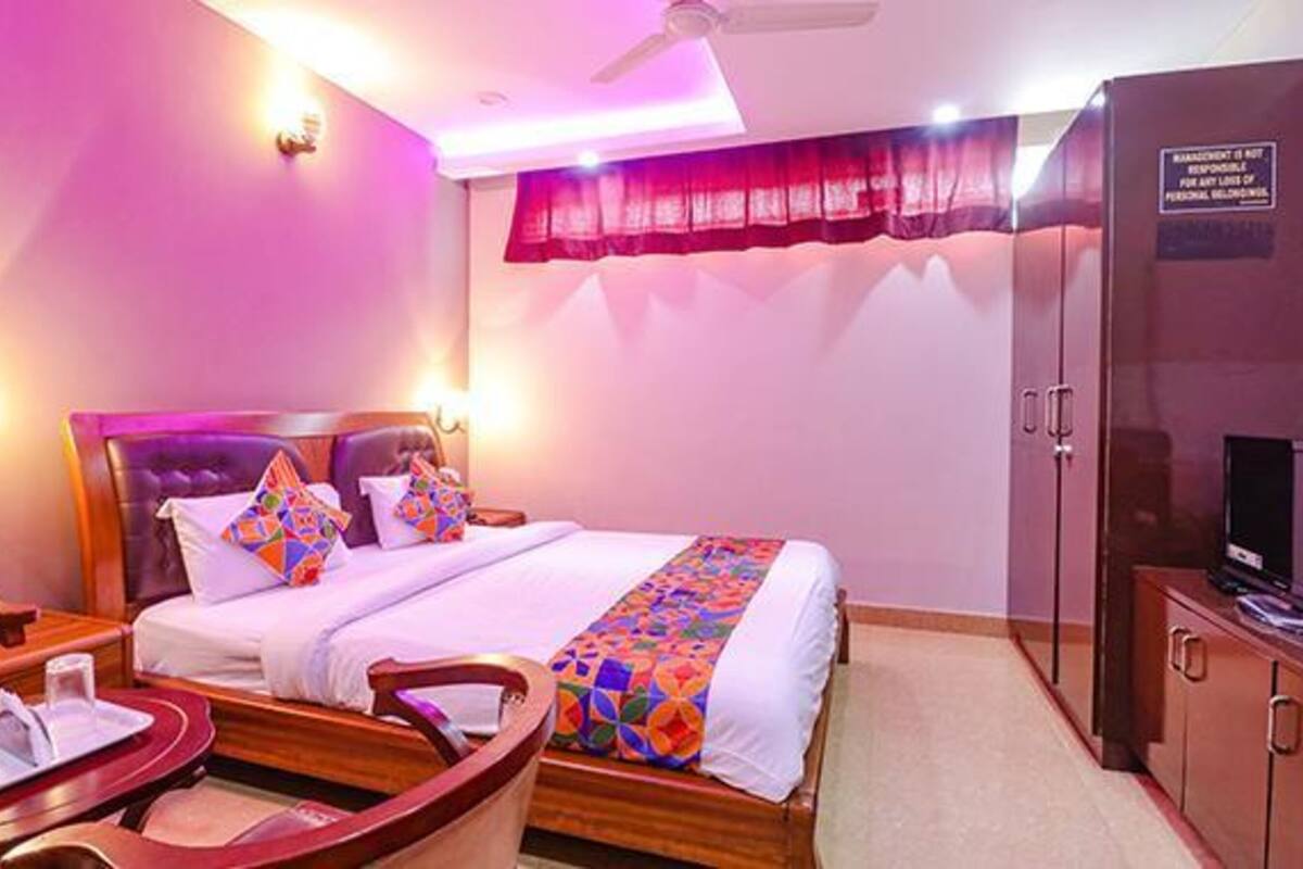 A hotel room with a bed, a TV, and a desk with a chair.